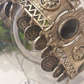 Keleties hatású, érmés fém karkötő.