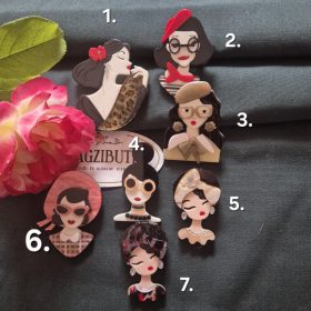 Női arc karakter kitűző fekete hajjal.