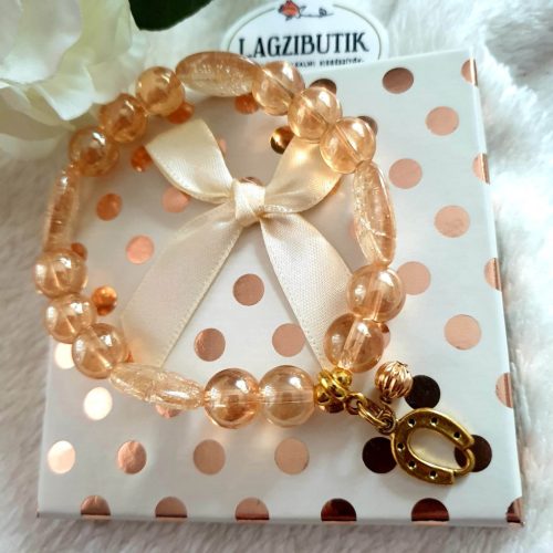 Patkó medálos bézs színű aura gyöngykarkötő, ovális gyöngyszemekkel.