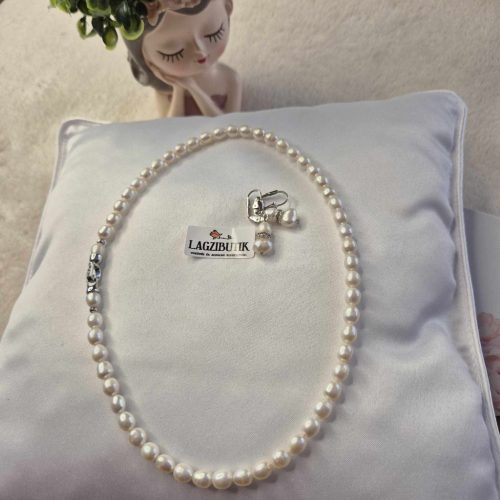 Törtfehér, rizsszemű édesvízi igazgyöngy-szett, cirkónia köves ékszerkapoccsal.