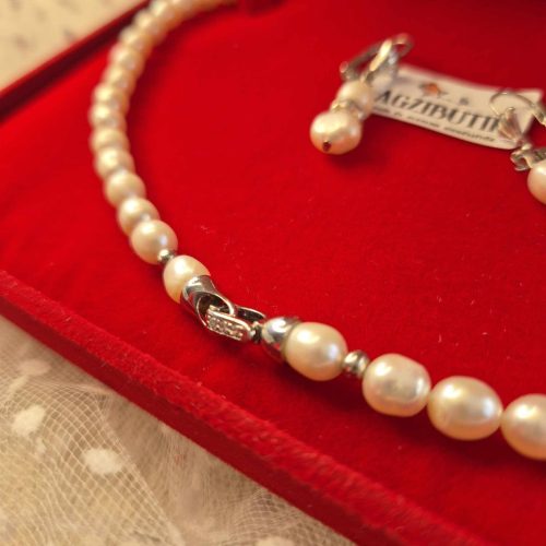 Törtfehér, rizsszemű édesvízi igazgyöngy-szett, cirkónia köves ékszerkapoccsal.